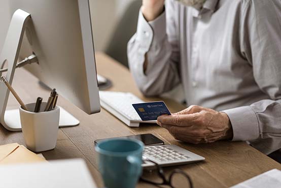 image of man sitting in front of a computer looking at a credit card