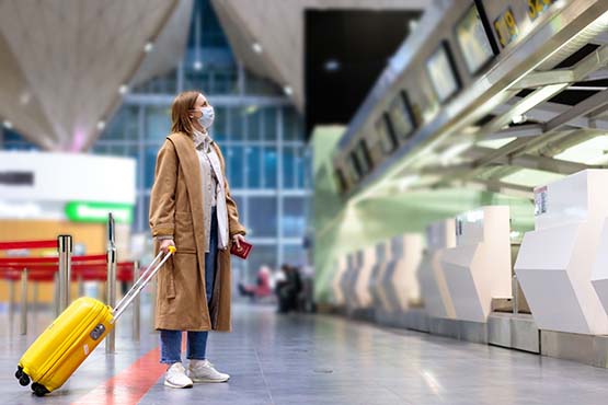 image of woman at the airport with suitcase looking at arrival and departure boards