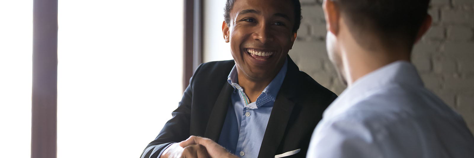 A businessman smiling and shaking someone's hand.